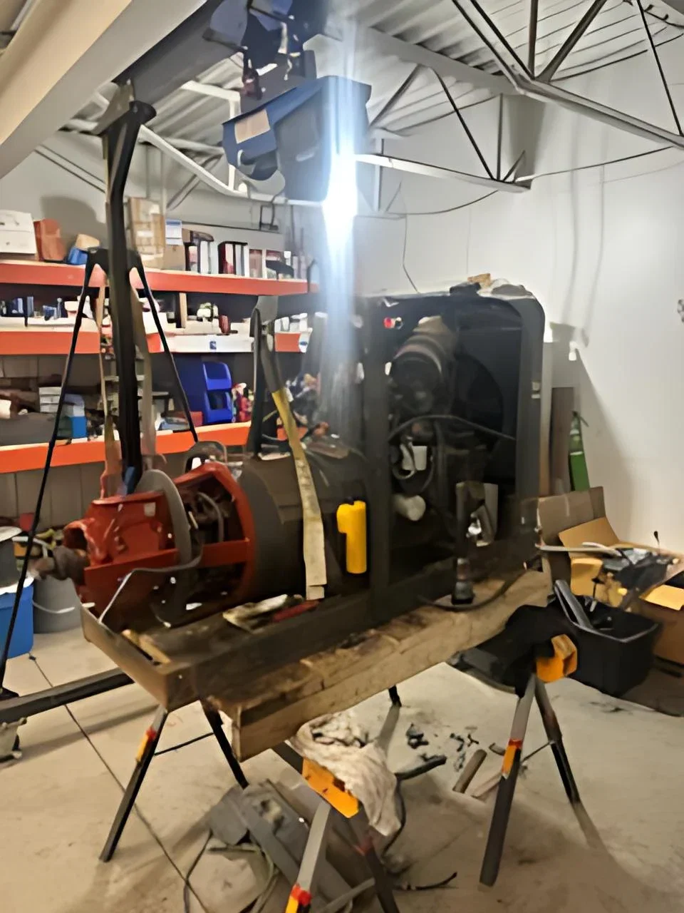 An engine-driven generator on a repair stand under a work light inside the 1st Choice shop